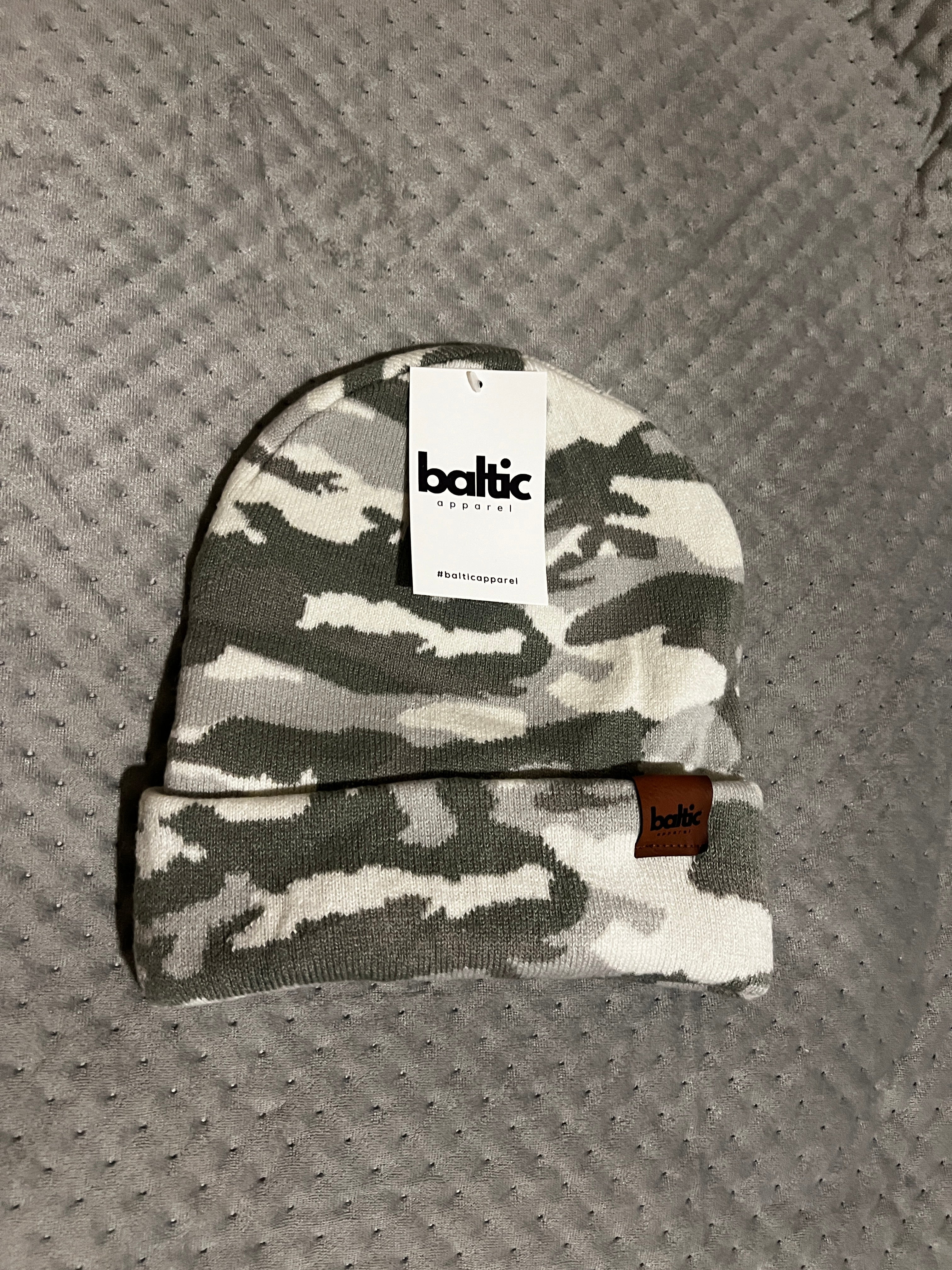 Camouflage-patterned product with a label on a textured gray surface